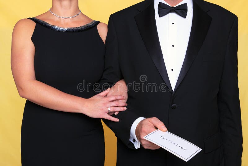 Photo of a couple in black tie evening wear, the men is holding an invitation. Photo of a couple in black tie evening wear, the men is holding an invitation.