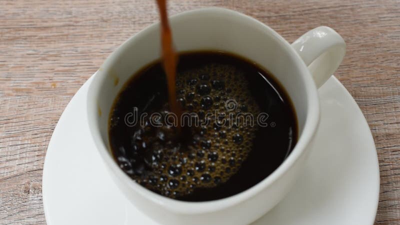 μαύρος καφές που ρέει από βάζο σε φλιτζάνι στο τραπέζι