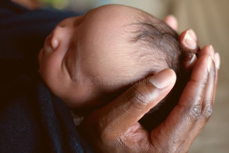 Black father holding newborn baby's head in his hands. Black father holding newborn baby's head in his hands