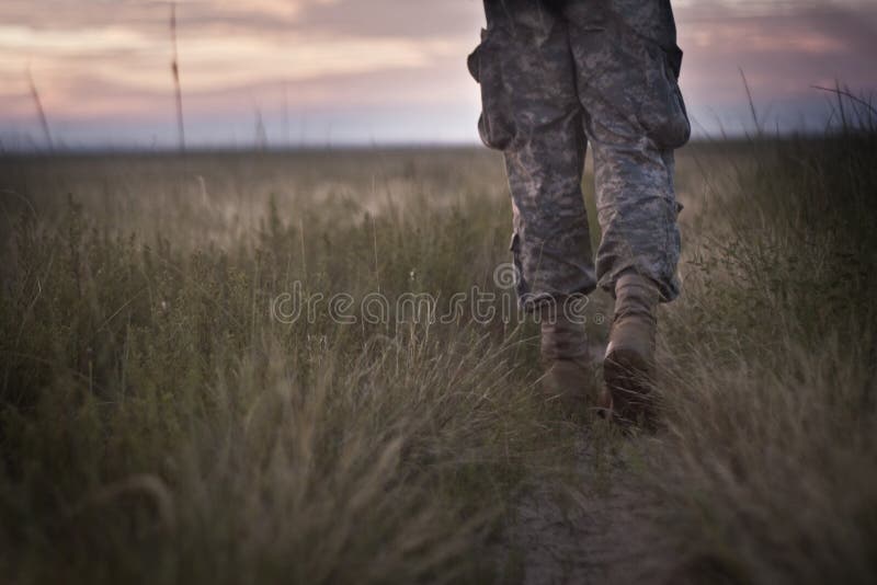 Person in camouflage walking towards a horizon. Person in camouflage walking towards a horizon.