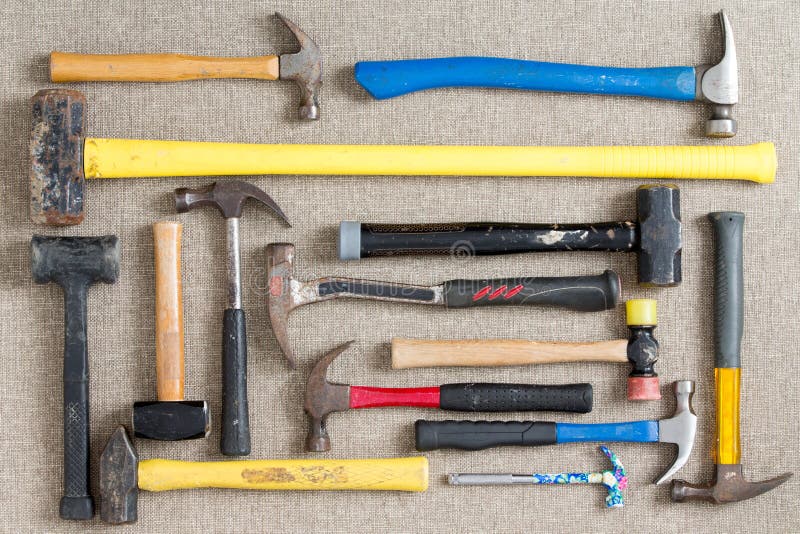 Large selection of different hammers and mallets arranged on a neutral beige background viewed from above in a DIY, renovation, maintenance,and construction concept. Large selection of different hammers and mallets arranged on a neutral beige background viewed from above in a DIY, renovation, maintenance,and construction concept