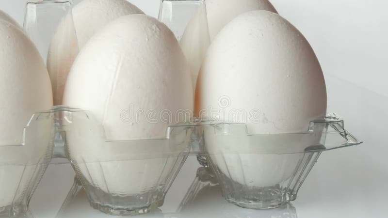 Μεγάλα άσπρα αυγά κοτόπουλου στο διαφανή πλαστικό δίσκο σε ένα άσπρο υπόβαθρο