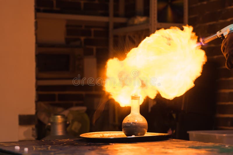 Lab technician setting fire to a ball with hydrogen blowtorch. Lab technician setting fire to a ball with hydrogen blowtorch