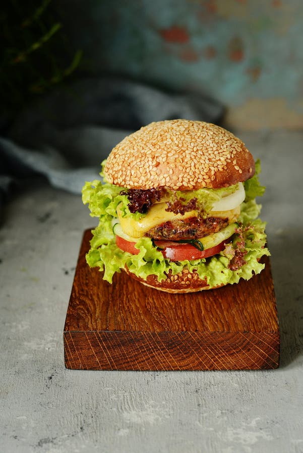 Μεγάλο burger με cutlet, τα λαχανικά και έναν φρέσκο ρόλο Σάντουιτς για το γρήγορο φαγητό προγευμάτων Εξυπηρέτηση ενός πρόχειρου στοκ εικόνες Μεγάλο burger με cutlet, τα λαχανικά και έναν φρέσκο ρόλο Σάντουιτς για το γρήγορο φαγητό προγευμάτων Εξυπηρέτηση ενός πρόχειρου στοκ εικόνες