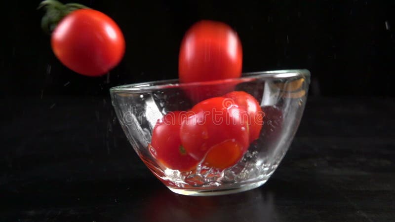 Μειωμένες ντομάτες κερασιών στο κύπελλο γυαλιού, σε αργή κίνηση 250 fps