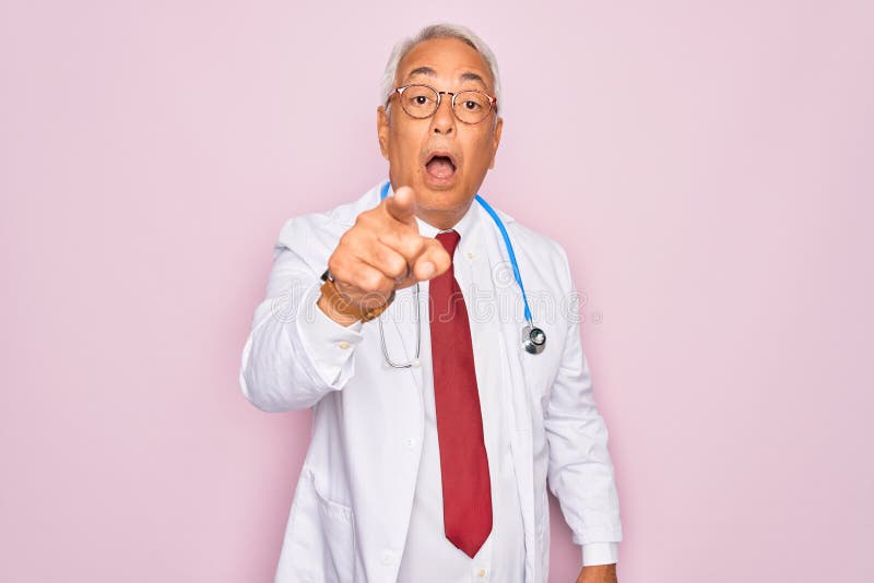 Middle age senior grey-haired doctor man wearing stethoscope and professional medical coat pointing displeased and frustrated to the camera, angry and furious with you. Middle age senior grey-haired doctor man wearing stethoscope and professional medical coat pointing displeased and frustrated to the camera, angry and furious with you