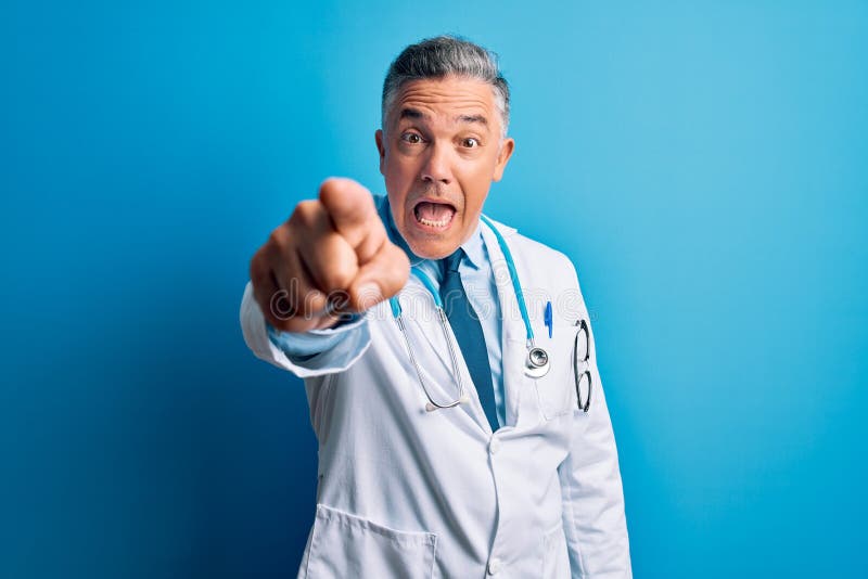 Middle age handsome grey-haired doctor man wearing coat and blue stethoscope pointing displeased and frustrated to the camera, angry and furious with you. Middle age handsome grey-haired doctor man wearing coat and blue stethoscope pointing displeased and frustrated to the camera, angry and furious with you