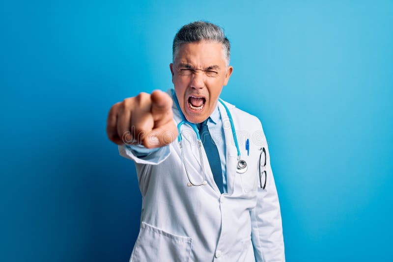 Middle age handsome grey-haired doctor man wearing coat and blue stethoscope pointing displeased and frustrated to the camera, angry and furious with you. Middle age handsome grey-haired doctor man wearing coat and blue stethoscope pointing displeased and frustrated to the camera, angry and furious with you