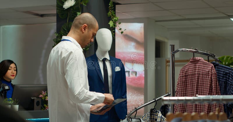 Μεσανατολίτης εργάτης ελέγχει τα αποθέματα δισκίων σε κατάστημα ενδυμάτων στοκ εικόνα
