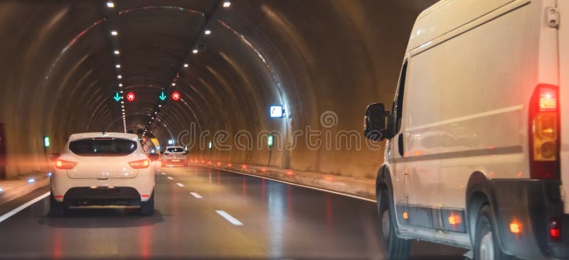 μεταφορές με μίνι λεωφορείο μέσω της σήραγγας μεταξύ άλλων αυτοκινήτων και με έγχρωμα φώτα στοκ εικόνα