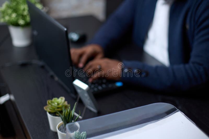 μη αναγνωρίσιμος αφρικανός επιχειρηματίας που εργάζεται σε ένα μαύρο φορητό υπολογιστή σε ένα σύγχρονο γραφείο στοκ φωτογραφία