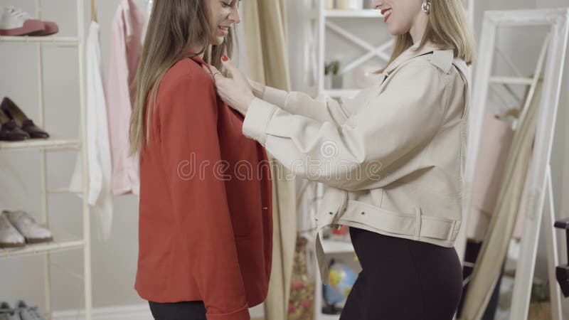 μη αναγνωρίσιμος, γεμάτος αυτοπεποίθηση χαμογελαστός ράφτης ή μοδάτο που βοηθάει τον πελάτη στο atelier. όψη των λεπτών νεαρών καυ απόθεμα βίντεο