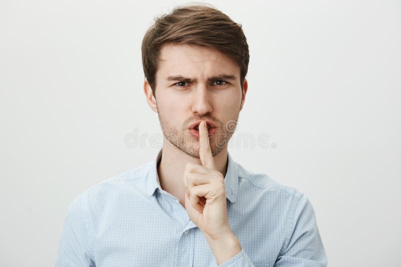 Μην προκαλέστε το θόρυβο, shh Πορτρέτο του ακριβούς σοβαρού όμορφου τύπου στον περιστασιακό μπλε αντίχειρα εκμετάλλευσης πουκάμισ στοκ εικόνα με δικαίωμα ελεύθερης χρήσης Μην προκαλέστε το θόρυβο, shh Πορτρέτο του ακριβούς σοβαρού όμορφου τύπου στον περιστασιακό μπλε αντίχειρα εκμετάλλευσης πουκάμισ στοκ εικόνα με δικαίωμα ελεύθερης χρήσης