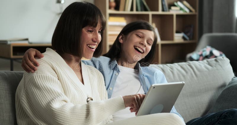 μητέρα και γιος χρησιμοποιώντας έναν υπολογιστή tablet και μοιράζοντας γέλιο στο σαλόνι