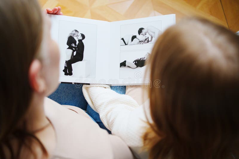μητέρα και κόρη γυρίζουν μέσα από ένα βιβλίο με φωτογραφίες του μπαμπά και της εγκύου μαμάς. στοκ φωτογραφία με δικαίωμα ελεύθερης χρήσης