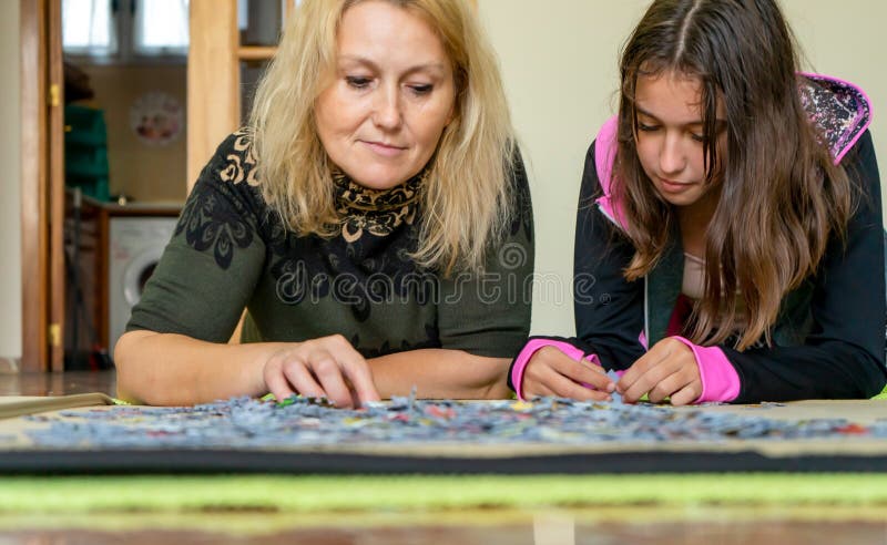 μητέρα και κόρη ξαπλωμένοι στο πάτωμα κάνοντας ένα παζλ μαζί, ενώ περνούν καλά σε μια βραδιά κοριτσιών στοκ εικόνα με δικαίωμα ελεύθερης χρήσης