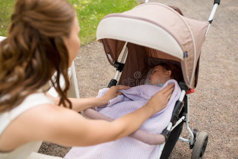 Μητέρα με το παιδί στον περιπατητή στο θερινό πάρκο στοκ φωτογραφία με δικαίωμα ελεύθερης χρήσης Μητέρα με το παιδί στον περιπατητή στο θερινό πάρκο στοκ φωτογραφία με δικαίωμα ελεύθερης χρήσης