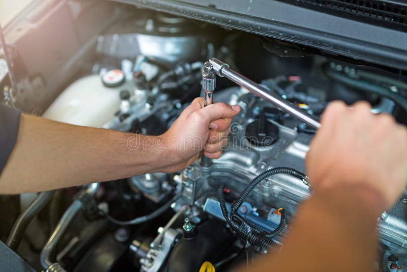 Hands of mechanic working on car engine in auto repair shop. Hands of mechanic working on car engine in auto repair shop