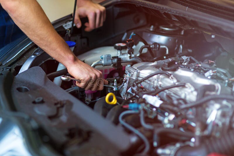 Hands of mechanic working on car engine in auto repair shop. Hands of mechanic working on car engine in auto repair shop