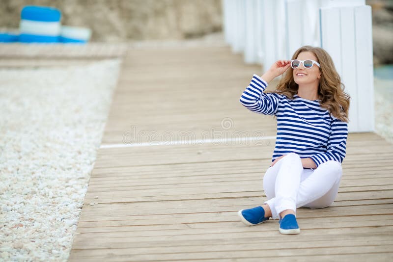 Μια γοητευτική αρκετά νέα γυναίκα hipster στη θερινή άσπρη μπλούζα στα πάνινα παπούτσια στα καθιερώνοντα τη μόδα τζιν στα μοντέρν στοκ εικόνες με δικαίωμα ελεύθερης χρήσης Μια γοητευτική αρκετά νέα γυναίκα hipster στη θερινή άσπρη μπλούζα στα πάνινα παπούτσια στα καθιερώνοντα τη μόδα τζιν στα μοντέρν στοκ εικόνες με δικαίωμα ελεύθερης χρήσης