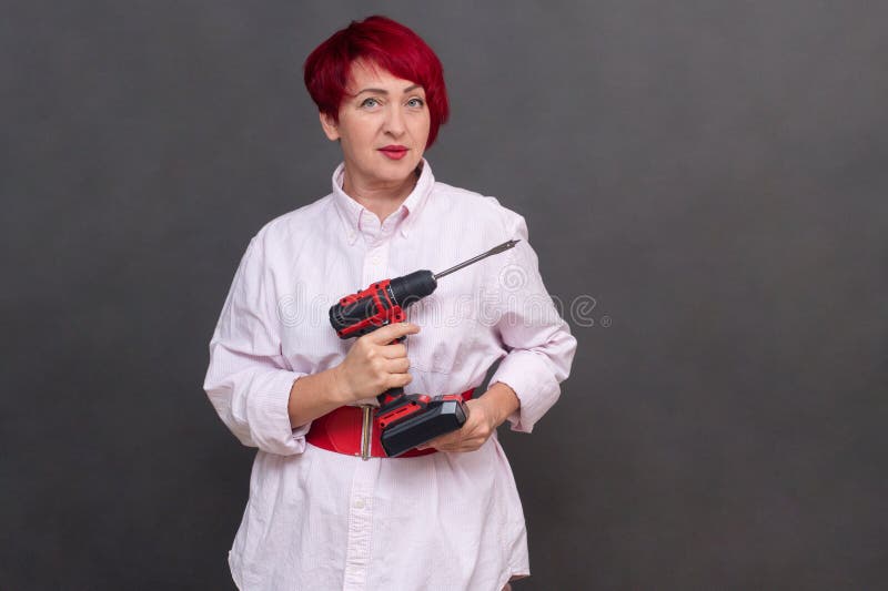 μια γυναίκα κρατά ένα κατσαβίδι στα χέρια της σε γκρι φόντο. μακέτα στοκ φωτογραφίες με δικαίωμα ελεύθερης χρήσης