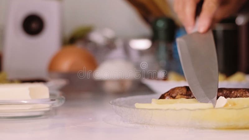 Μια γυναίκα με ένα μαχαίρι βάζει το βούτυρο σε ένα πιάτο με τα τρόφιμα φιλμ μικρού μήκους