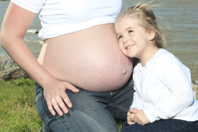 Μια ευτυχής έγκυος γυναίκα έξω με είναι παιδί