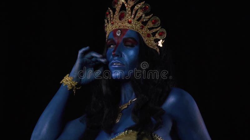 Μια ινδή θεά Kali με χρυσά ρούχα ποζάρει σε μαύρο φόντο