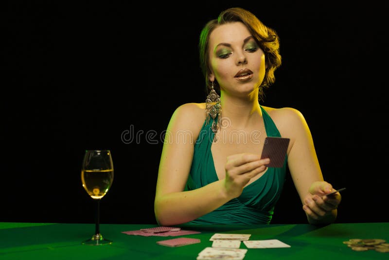 A young lady in a green dress is playing solitaire made from scrying cards on a table on a green card cloth. A young lady in a green dress is playing solitaire made from scrying cards on a table on a green card cloth.