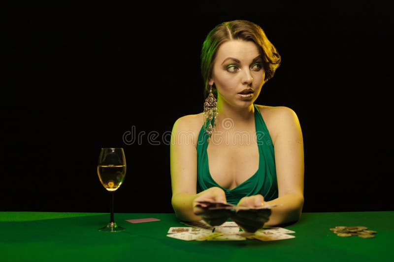 A young lady in a green dress is playing solitaire made from scrying cards on a table on a green card cloth. A young lady in a green dress is playing solitaire made from scrying cards on a table on a green card cloth.