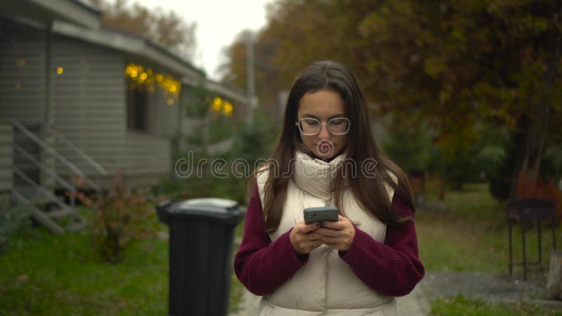 Μια νεαρή γυναίκα βαθιά μπλεγμένη στο smartphone της, ενώ απολαμβάνει το εξωτερικό σε μια φωτεινή μέρα απόθεμα βίντεο