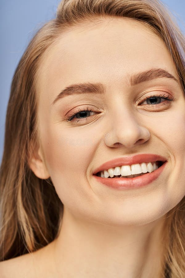A young blonde woman smiles joyfully while showing white teeth in a studio setting., stock photo. A young blonde woman smiles joyfully while showing white teeth in a studio setting., stock photo