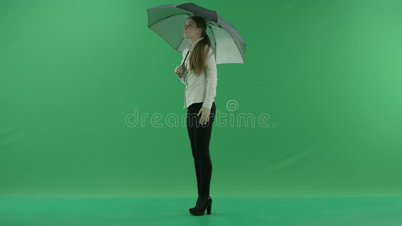Μια στοχαστική γυναίκα περιμένει τη μόνιμη αριστερή πλευρά με την ομπρέλα πέρα από την πράσινη οθόνη r