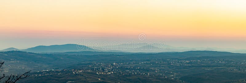 Μια συναρπαστική πανοραμική θέα των λόφων και των μακρινών βουνών ξεθάφτηκε στις ζεστές αποχρώσεις του ηλιοβασίλεμα. Η απαλή διαβά στοκ εικόνες