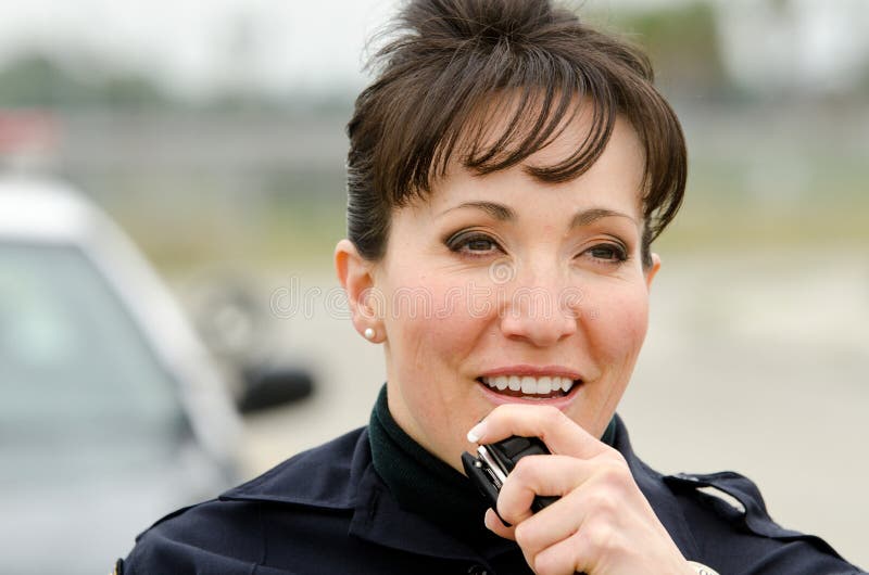 A friendly and smiling Hispanic female officer as she talks on her radio. A friendly and smiling Hispanic female officer as she talks on her radio.