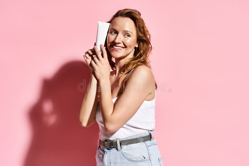 A graceful woman in a white tank top holding cream with focus and ease, embodying natural beauty and modern connectivity, stock photo. A graceful woman in a white tank top holding cream with focus and ease, embodying natural beauty and modern connectivity, stock photo