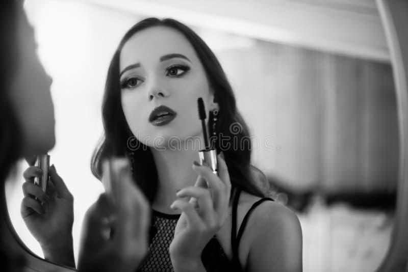 Μια όμορφη νέα γυναίκα γίνεται ένα makeover Κορίτσι με cerly την τρίχα που κάνει το βράδυ makeup που χρησιμοποιεί Mascara στοκ εικόνα Μια όμορφη νέα γυναίκα γίνεται ένα makeover Κορίτσι με cerly την τρίχα που κάνει το βράδυ makeup που χρησιμοποιεί Mascara στοκ εικόνα
