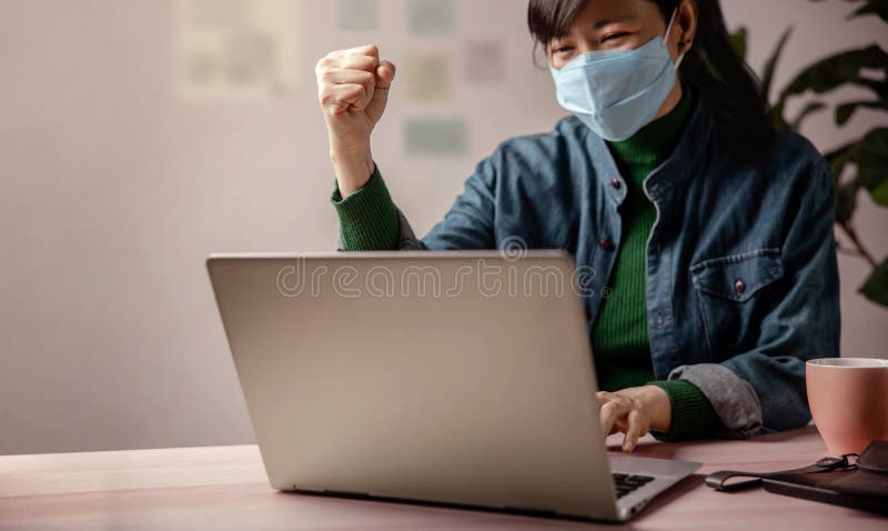 Small Business and Successful during Coronavirus Concept. blurred Gladful Business Woman wearing Mask, Working on Computer Laptop in Office. Focus on Hand. Business Achieves Goals. Celebrating Success. Small Business and Successful during Coronavirus Concept. blurred Gladful Business Woman wearing Mask, Working on Computer Laptop in Office. Focus on Hand. Business Achieves Goals. Celebrating Success