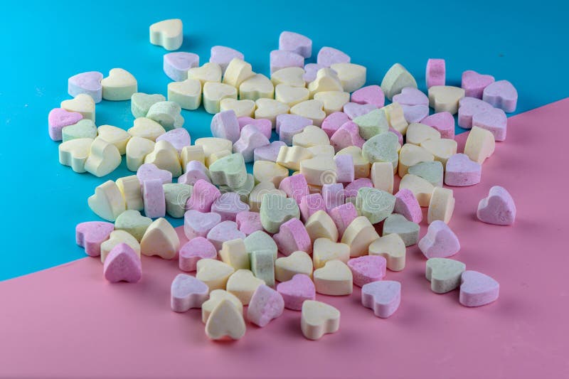 small heart-shaped candies on a blue-pink background 2. small heart-shaped candies on a blue-pink background 2