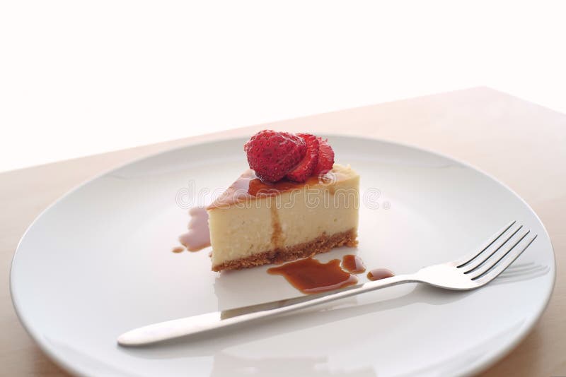 Μικρή φέτα cheesecake σε ένα μεγάλο πιάτο στοκ εικόνα Μικρή φέτα cheesecake σε ένα μεγάλο πιάτο στοκ εικόνα