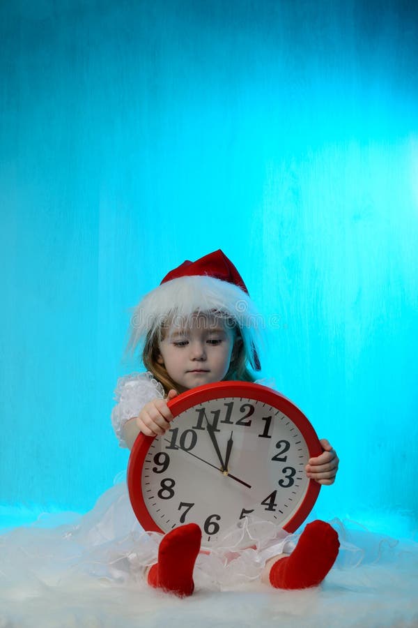 Μικρό κορίτσι στο καπέλο santa με το ρολόι στοκ εικόνα Μικρό κορίτσι στο καπέλο santa με το ρολόι στοκ εικόνα