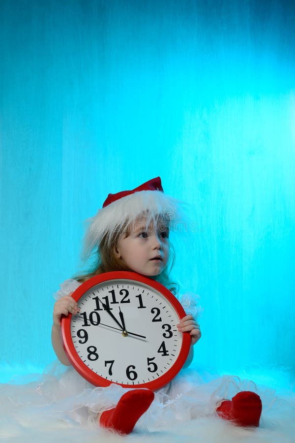 Μικρό κορίτσι στο καπέλο santa με το ρολόι στοκ εικόνες Μικρό κορίτσι στο καπέλο santa με το ρολόι στοκ εικόνες
