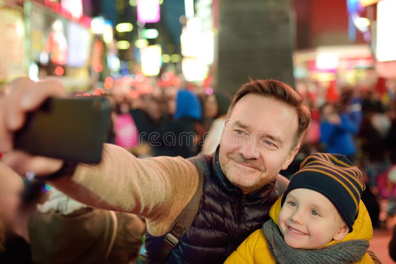 Μικρό παιδί και ο πατέρας του που παίρνουν selfie στη Times Square το βράδυ, το στο κέντρο της πόλης Μανχάταν στοκ εικόνα με δικαίωμα ελεύθερης χρήσης Μικρό παιδί και ο πατέρας του που παίρνουν selfie στη Times Square το βράδυ, το στο κέντρο της πόλης Μανχάταν στοκ εικόνα με δικαίωμα ελεύθερης χρήσης