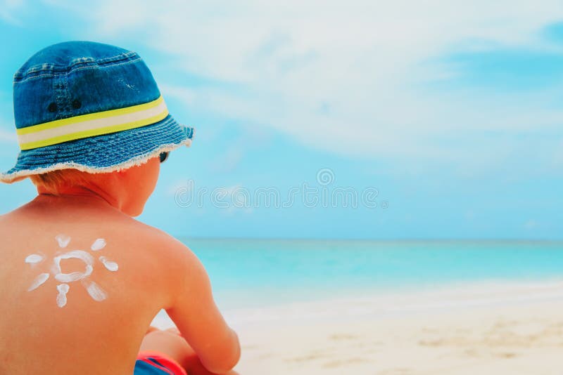 Μικρό παιδί προστασίας ήλιων με το suncream στην τροπική παραλία στοκ εικόνες