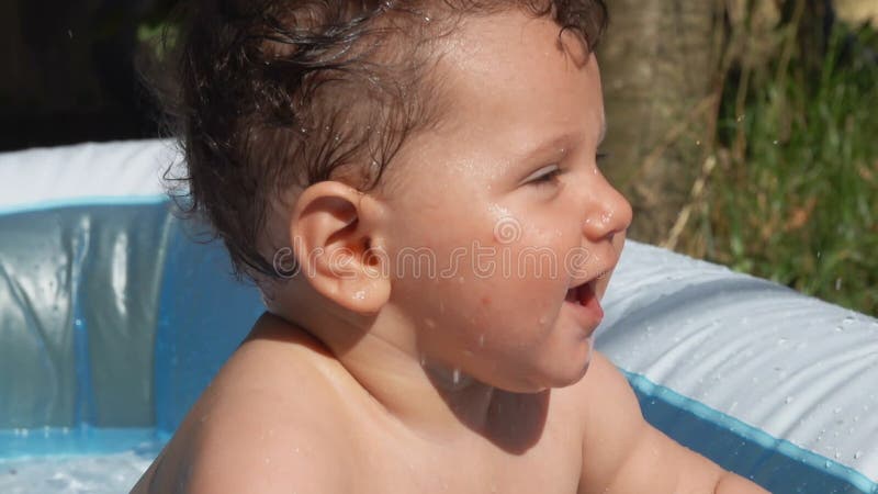 μικρό χαριτωμένο παιδί λουτρό σε φουσκωτή πισίνα στην πίσω αυλή