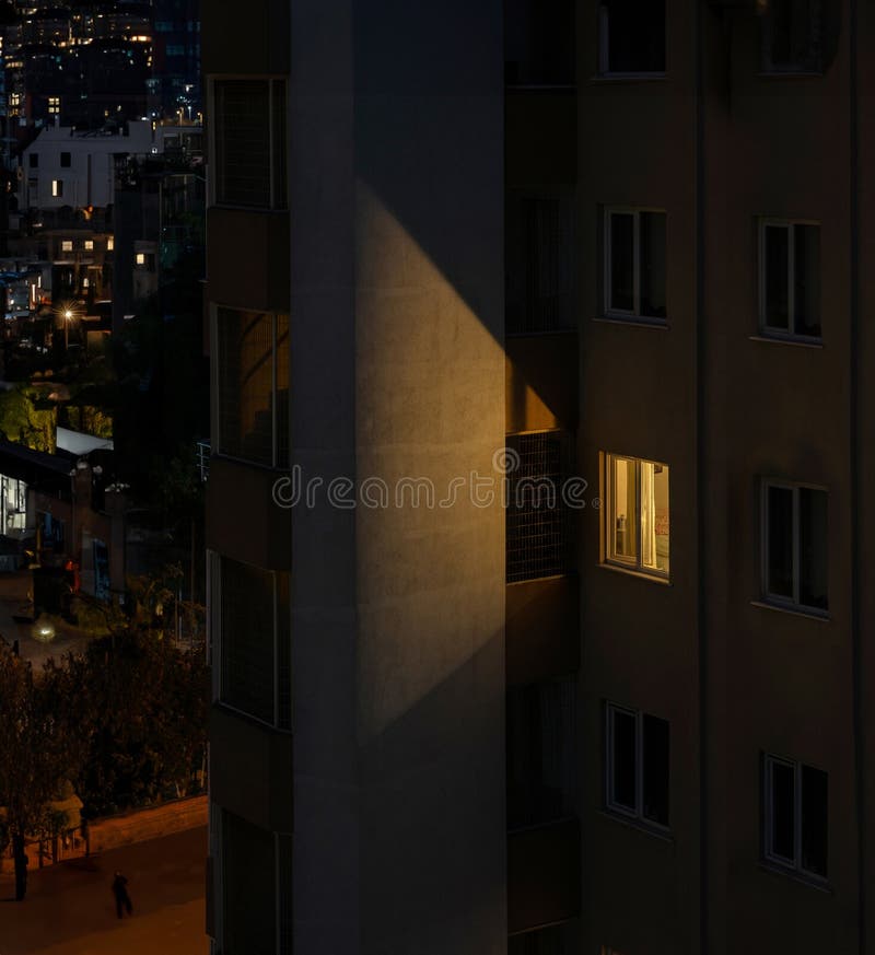 μοναχικό φωτισμένο παράθυρο φωτίζει την έξοδο κινδύνου στη νυχτερινή σκηνή του διαμερίσματος στοκ φωτογραφία