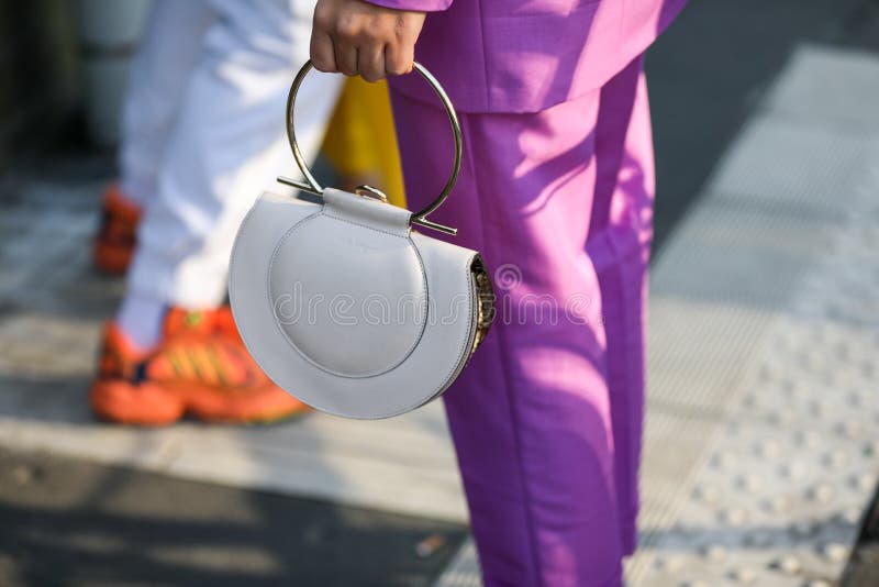 February 19, 2020: model wears a pair of purple pants and a white crescent handbag during the Gucci fashion show at the women`s fashion week fall / winter 2020 in Milan. February 19, 2020: model wears a pair of purple pants and a white crescent handbag during the Gucci fashion show at the women`s fashion week fall / winter 2020 in Milan