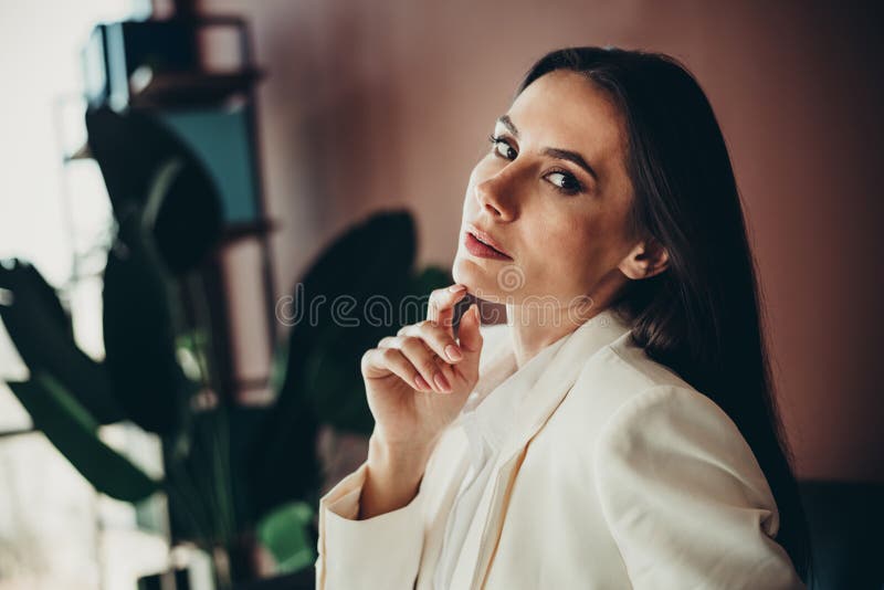 Μοντέρνα νεαρή επαγγελματίας επιχειρηματίας με κομψή λευκή φορεσιά με σιγουριά σε μοντέρνο γραφείο στοκ εικόνες