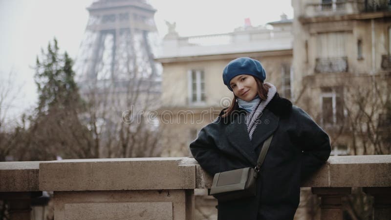 Μοντέρνη γυναίκα beret και παλτό που στέκεται στη λεωφόρο από τον πύργο του Άιφελ στο Παρίσι