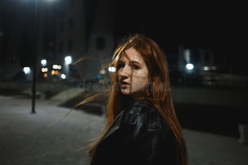 Μοντέρνη νέα redhead τοποθέτηση γυναικών στην πόλη νύχτας στοκ εικόνα Μοντέρνη νέα redhead τοποθέτηση γυναικών στην πόλη νύχτας στοκ εικόνα